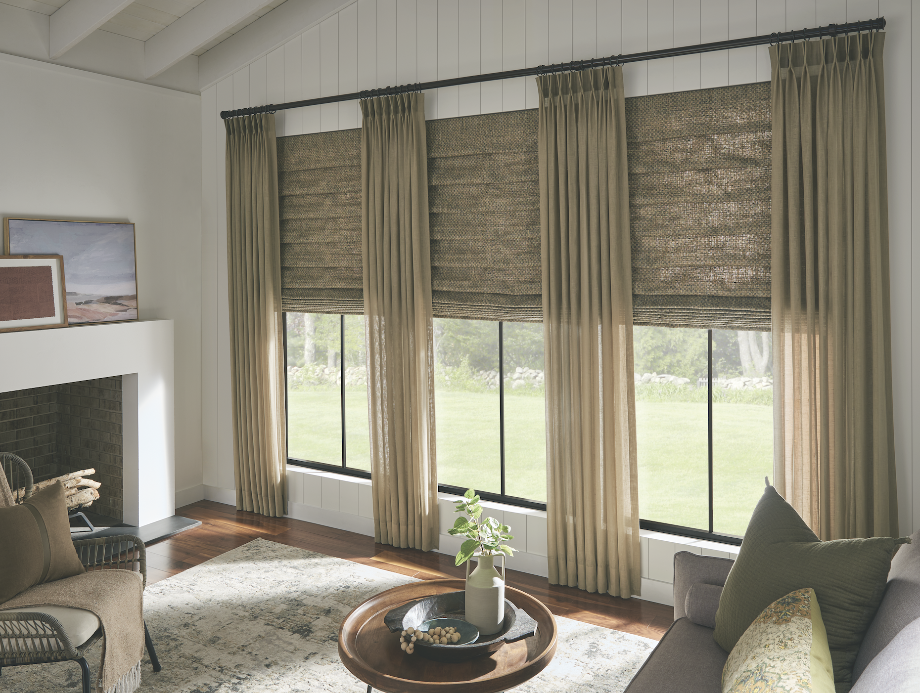 Sheer drapery with woven roman shades over a garden view